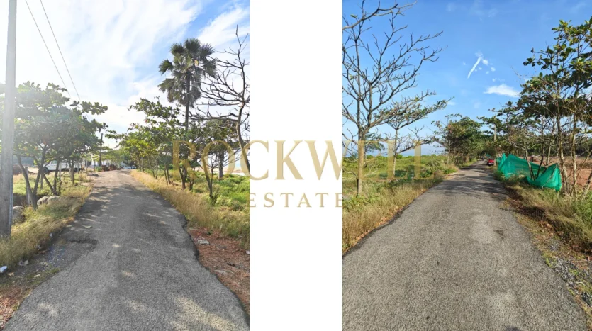 Real photograph of the access road leading to Rohan Marina One project surrounded by trees and greenery.